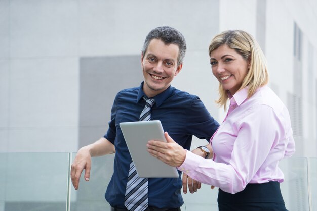 Happy excited business people looking at camera and standing on office building roof.