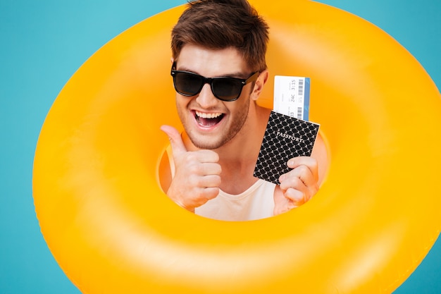 Happy excited man in sunglasses looking through inflatable ring