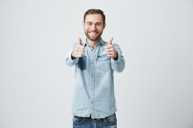 Felice uomo eccitato con la barba che mostra il pollice in alto gesto,