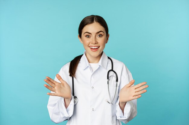 Happy and excited smiling young woman looking with excitement and surprised standing in white lab co...