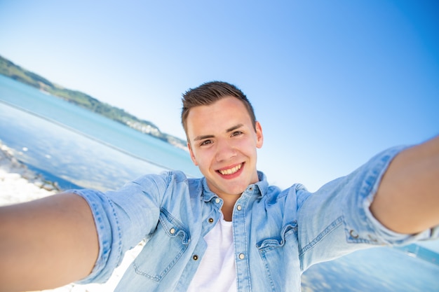 Foto gratuita ragazzo turistico emozionante felice che prende selfie in mare
