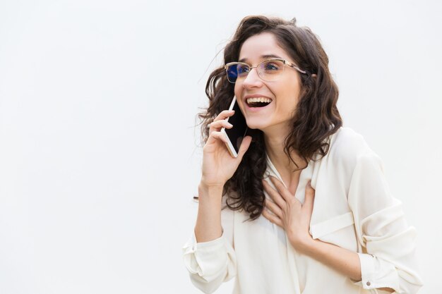 Счастливая взволнованная женщина в очках разговаривает по мобильному телефону