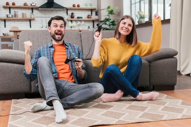 Happy excited young couple cheering after winning playing video game