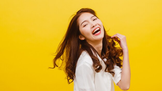 Happy excited young funny Asian lady listening to music and dancing in casual clothing over yellow wall. Human emotions, facial expression, studio portrait, lifestyle concept.