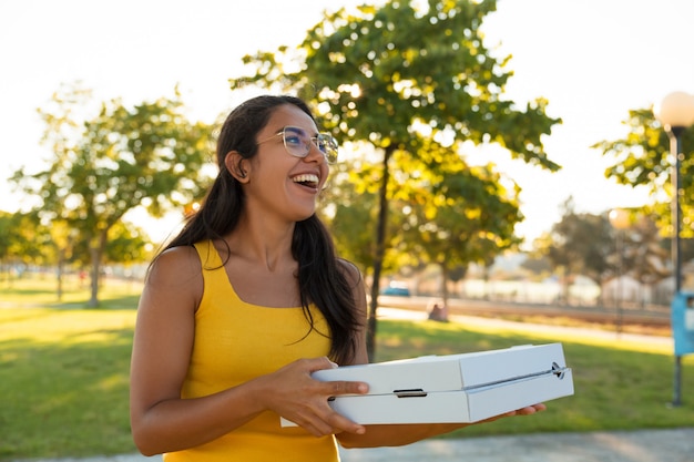 Happy excited young woman carrying pizza for outdoor party