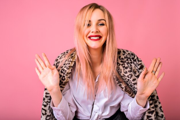 Happy exited young hipster girl with pink trendy hairs and bright make up ready for celebration, winter fur leopard coat, positive mood, ready for celebration.