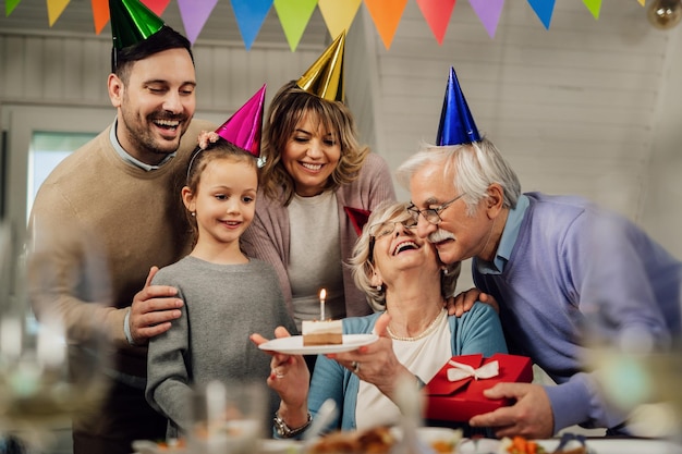 Счастливая большая семья празднует день рождения пожилой женщины и удивляет ее тортом