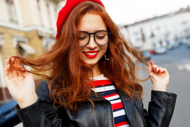 Счастливая сказочная рыжая женщина в стильном красном берете на улице