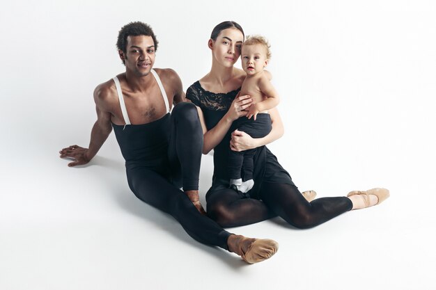 A happy family in black clothing sitting on the floor