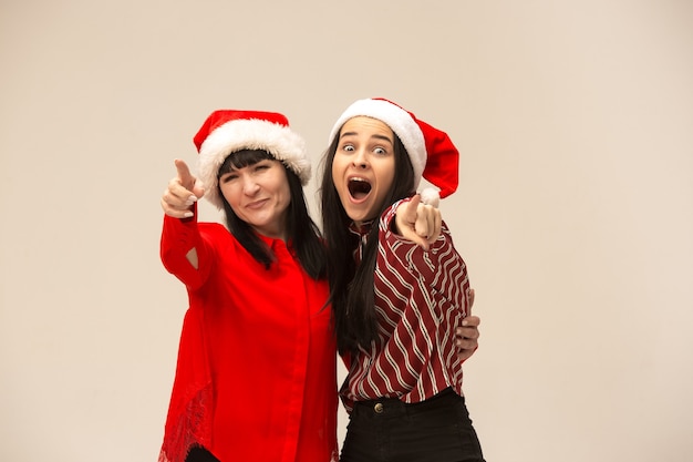 Happy family in Christmas sweater posing. Enjoying love hugs, holidays people. Mom and doughter on a gray background in the studio