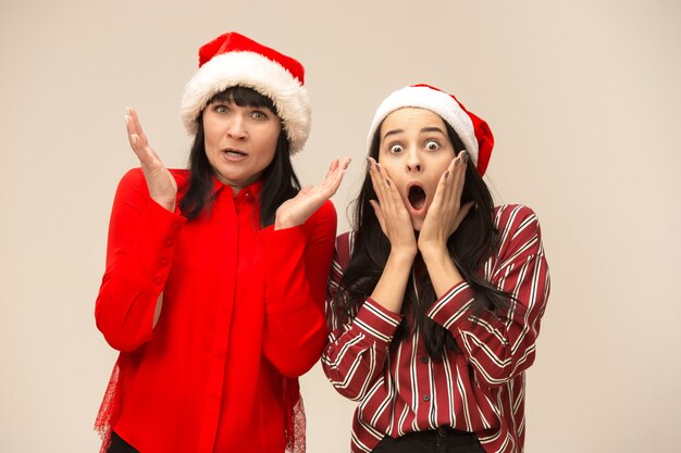 Happy family in Christmas sweater posing. Enjoying love hugs, holidays people. Mom and doughter on a gray background in the studio