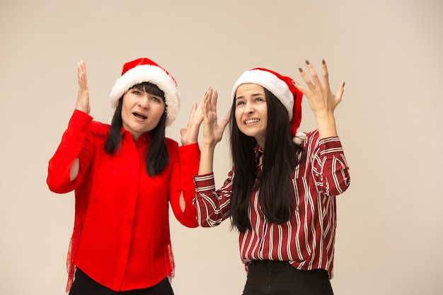 Happy family in Christmas sweater posing. Enjoying love hugs, holidays people. Mom and doughter on a gray background in the studio