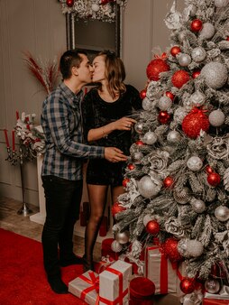飾られたクリスマスツリーと花輪で新年とクリスマスを祝う幸せな家族のカップル