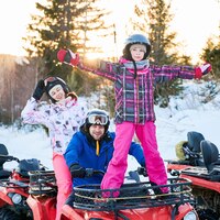 Happy family driving quad bike in winter mountains