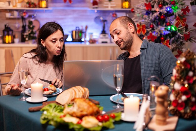 ダイニングテーブルに座っておいしいクリスマスディナーを食べる幸せな家族