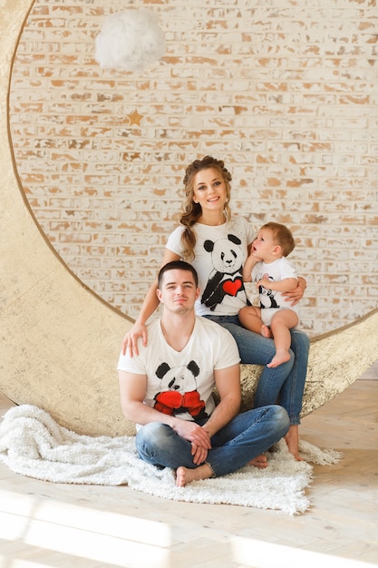 Happy family father, mother and child son near a blank brick wall in the room.