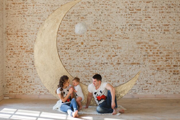 Happy family father, mother and child son near a blank brick wall in the room. 