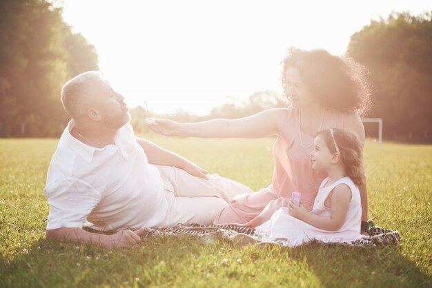 Счастливая семья, отец матери и дочери ребенка в природе на закате
