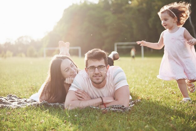 Happy family, father of mother and daughter of baby in the nature at sunset