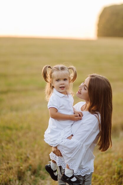 Happy family in a field in autumn. Mother, father and baby play in nature in the rays of sunset