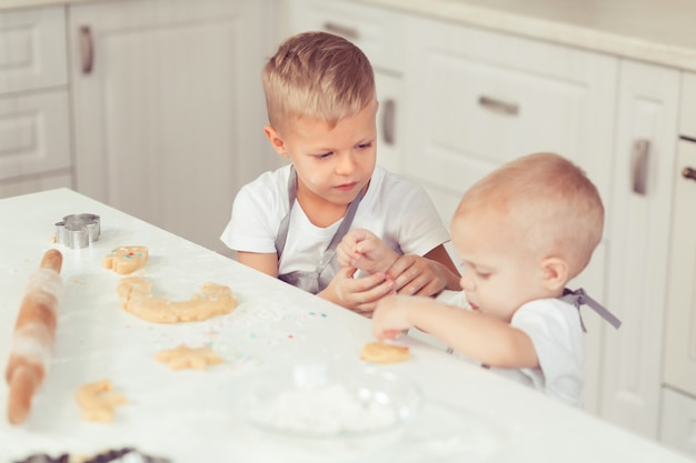 幸せな​家族​の​面白い​兄弟​の​子供たち​は​生地​を​準備し​、​キッチン​で​クッキー​を​焼く
