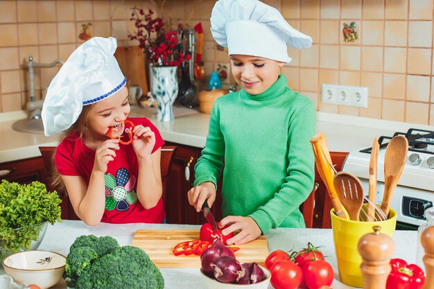 Счастливая семья веселые дети готовят салат из свежих овощей на кухне