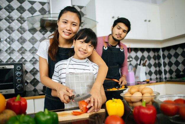 Счастливая семья помогает приготовить еду вместе на кухне дома.
