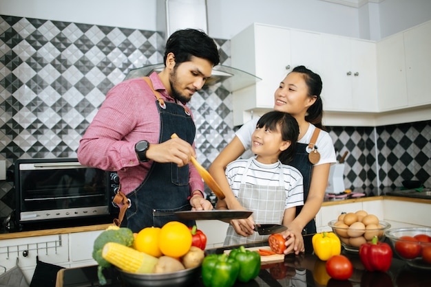 Счастливая семья помогает приготовить еду вместе на кухне дома.