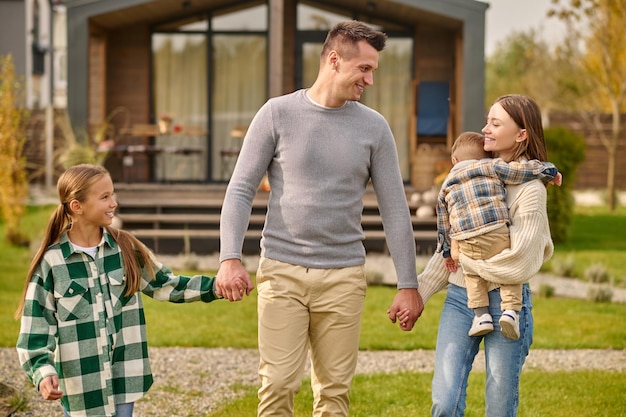 Famiglia felice che si tiene per mano camminando nel cortile