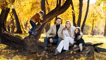 happy family in an autumn park mother father and daughter are sitting on a tree trunk