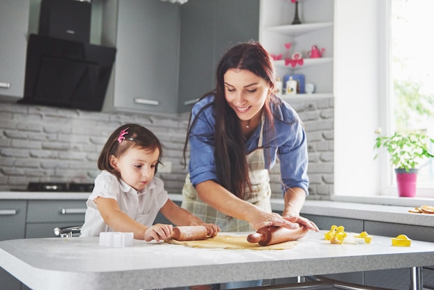 Happy family in the kitchen. Holiday food concept. Mother and daughter preparing the dough, bake cookies. Happy family in making cookies at home. Homemade food and little helper