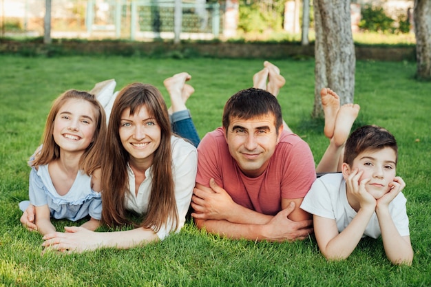 Happy family lying on green grass and looking at camera