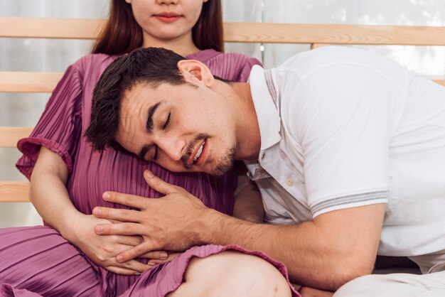 Happy Family New Parent Dad and MomHusband Listening on the Belly of His Wife to Hearing the Sound of Fetus