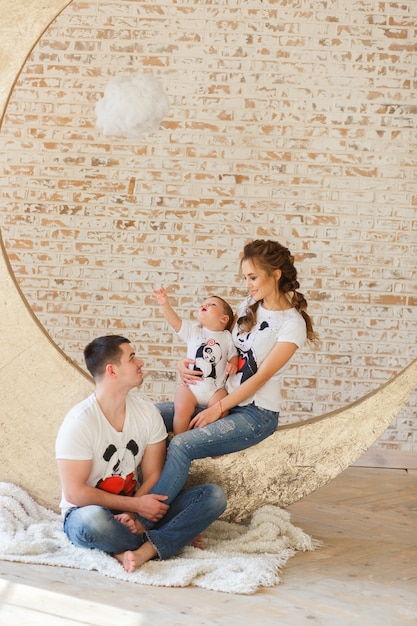 Happy family playing in minimalistic studio room with brick wall on background