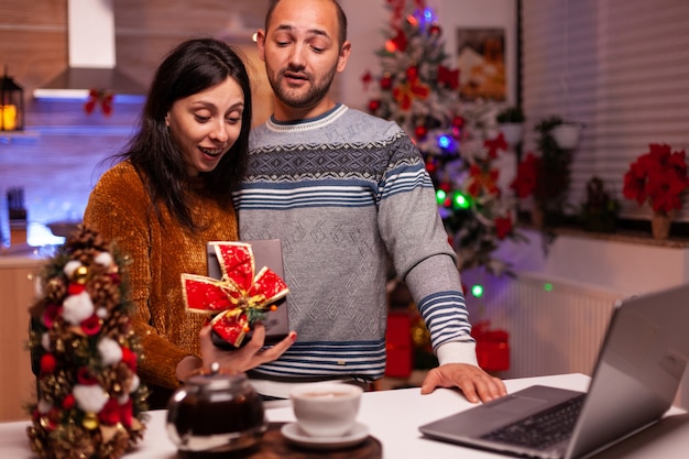 Happy family showing present gift with ribbon on it during online videocall