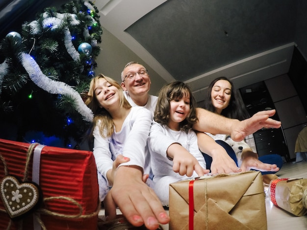 Happy family, sit on a floor near a fir-tree