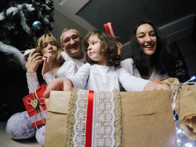 Happy family, sit on a floor near a fir-tree