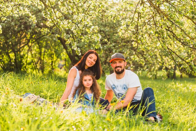 Happy family sitting on grass in spring