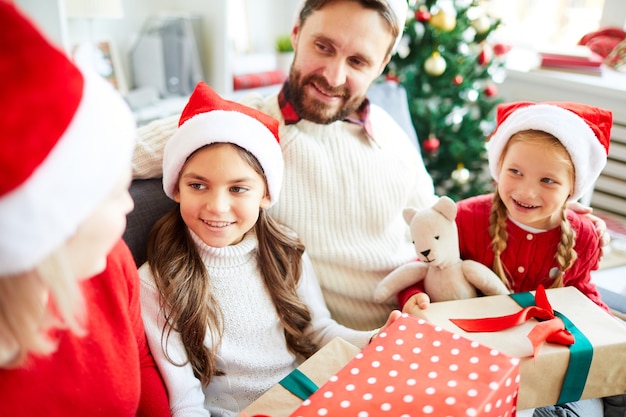 Happy family sitting on the sofa and unwrapping Christmas presents