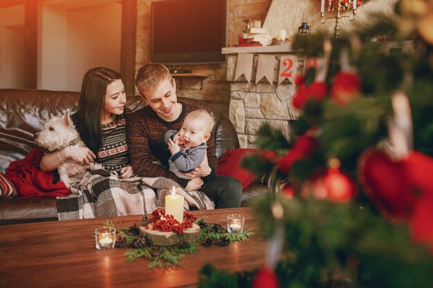 Happy family sitting on sofa with a christmas tree out of focus in front