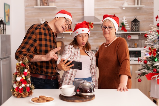 Happy family taking selfie using phone making funny expressions during photo
