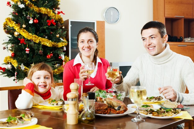 クリスマスディナーを持つ3人の幸せな家族