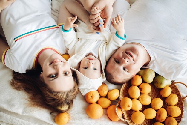 세 가지 과일을 좋아하는 행복한 가족은 소파에 누워 함께 삶을 즐깁니다.