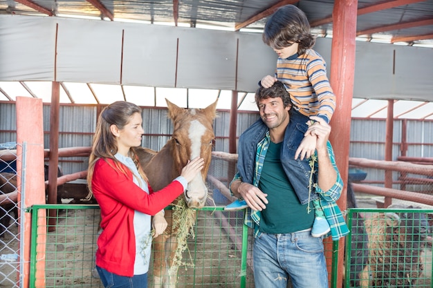 Happy family visiting the horse in the stable