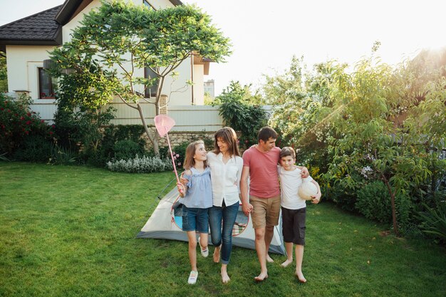 Happy family walking on grass in front of tent at outdoors