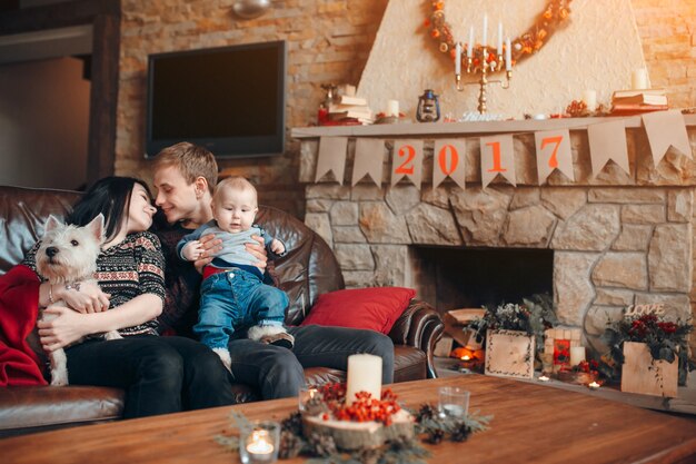 Happy family with a baby and a dog and beside him a chimney with the poster of 2017