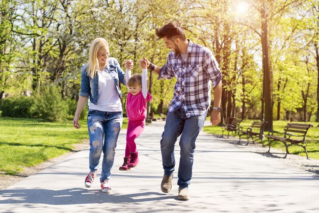 Happy family, young caucasian parents hiking with their daughter in a park