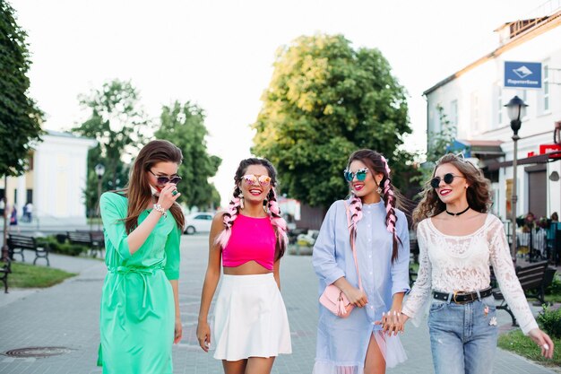 Happy fashionable women in colorful clothes walking at street.