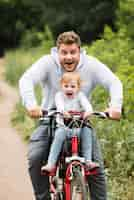 Foto gratuita felice padre e figlia in bicicletta