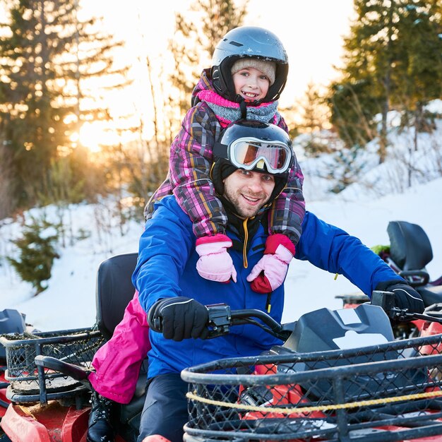 Happy father and daughter sitting on quad bike